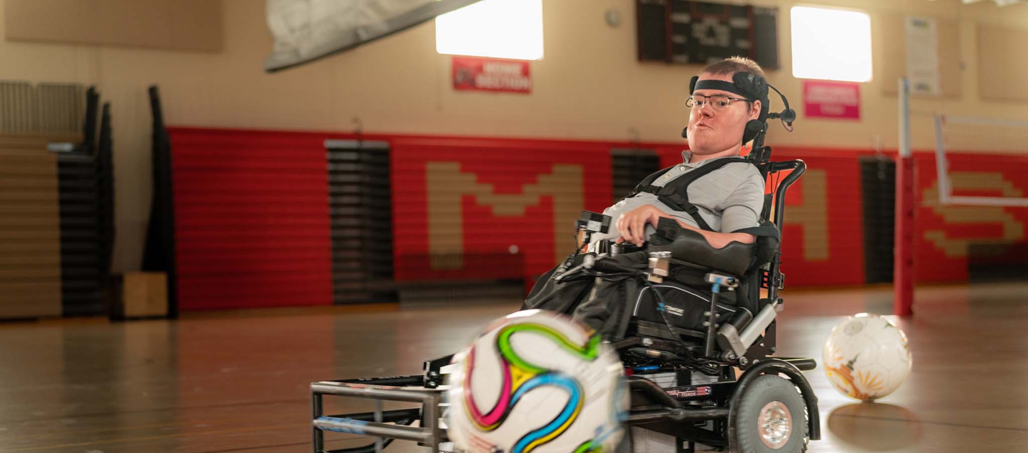 Nathan in a gymnasium playing with a soccer ball